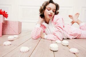 linda pequeño niña en pijama con dulces sentado en el piso foto