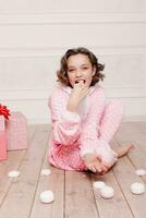 Cute little girl in pajama with sweets sitting on the floor photo