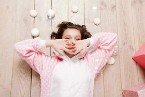 Cute little girl in pajama with sweets sitting on the floor photo