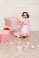 linda pequeño niña en pijama con dulces sentado en el piso foto