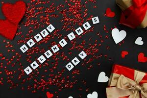 The concept of celebrating Valentine's Day. Inscription Happy Valentine's Day and gift boxes on a black background. photo