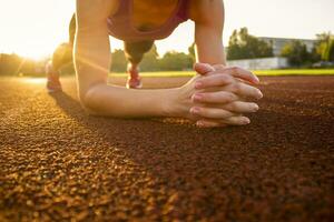 A young woman is training on the sports field. Plank exercise photo