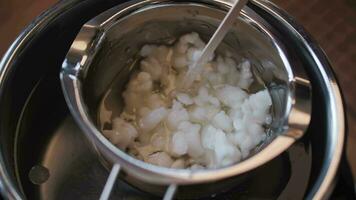 Soy wax flakes are stirred in a container to melt video