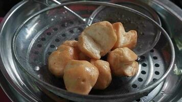 Closed up on Asian merchant hands is deep fried meatballs in a pot of boiling oil for sell delicious food to customers on street food in market of Thailand video