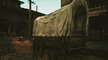 A rustic covered wagon parked next to a charming building in a scenic field video