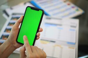 teléfono verde pantalla en mano, mano participación teléfono inteligente verde pantalla en casa, utilizando móvil teléfono verde pantalla foto
