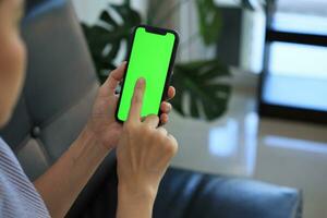 Phone green screen in hand, hand holding smartphone green screen in house, using mobile phone green screen photo