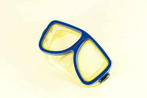 a blue and yellow diving mask on a white surface photo