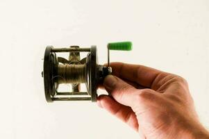 a person holding a fishing reel with a green handle photo