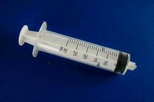 a syringe with a needle on a blue surface photo