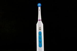 a white and blue electric toothbrush on a black background photo