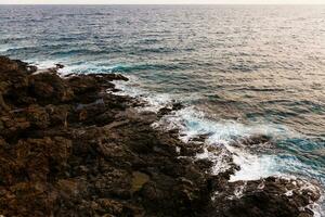 ocean waves hit and crash against stones photo