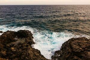 ocean waves hit and crash against stones photo