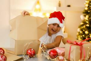 christmas, x-mas, winter, happiness concept - smiling girl in santa helper hat with gift box photo