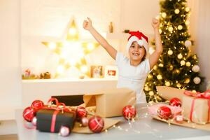 child girl in red hat preparing gifts for christmas at home, cozy holiday interior photo