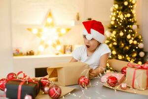 child girl in red hat preparing gifts for christmas at home, cozy holiday interior photo