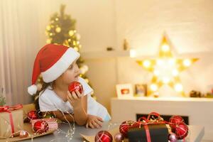 christmas, x-mas, winter, happiness concept - smiling girl in santa helper hat with gift box photo