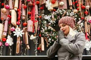 Gorgeous fashionable young blonde woman sitting near the window of the store or coffeehouse, dreaming, praying for a miracle before Christmas. cold winter day. photo