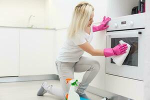 The girl on kitchen wipes an oven photo