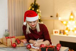 Attractive young woman going to write something to notepad, Christmas photo