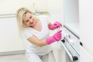 The girl on kitchen wipes an oven photo