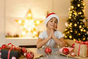 child girl in red hat preparing gifts for christmas at home, cozy holiday interior photo