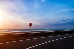 el la carretera vueltas a lo largo el playa a puesta de sol foto