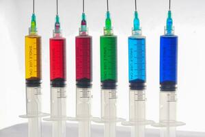 Syringes filled with colorful liquids are neatly arranged on an isolated background photo