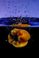 bell peppers on a dark background are dropped into the water causing a splash photo