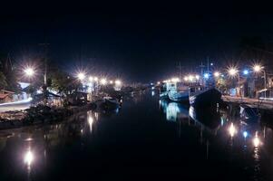 Upstream of the river at Pasuruan Harbor in Indonesia, many fishing boats dock at night photo