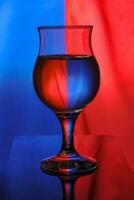 a wine glass filled with water on a two-color background creates light diffraction and reflection photo