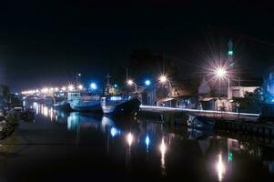 Upstream of the river at Pasuruan Harbor in Indonesia, many fishing boats dock at night photo