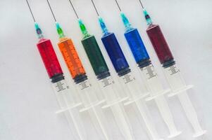 Syringes filled with colorful liquids are neatly arranged on an isolated background photo