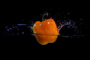 bell peppers are dropped into the water causing a splash photo