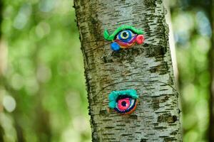 Art object of human eyes on tree trunk in green forest background, trees sight feeling ecological concept photo