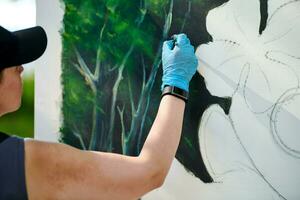 niña artista mano sostiene pintar cepillo y sorteos verde naturaleza paisaje en lona foto