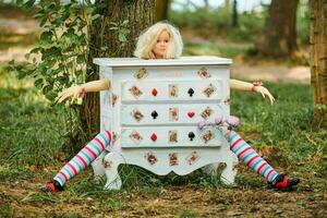 Dresser with doll Alice inside near Humpty Dumpty and mushrooms art object on outdoor art exhibition photo