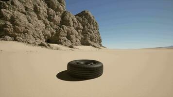 A tire laying on the sand in front of a mountain video