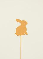 Decorative, wooden rabbit of orange color on a white background. photo