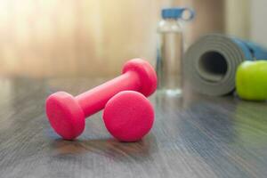 Red dumbbells on a wooden floor. Home workout concept photo