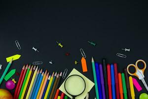 Multicolored stationery on a black background. Copy space. Back to school concept photo