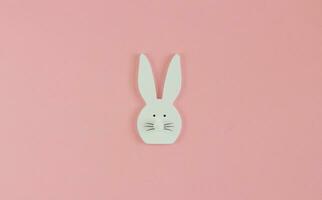 White wooden bunny on a rose background. Background for design. Copy space photo