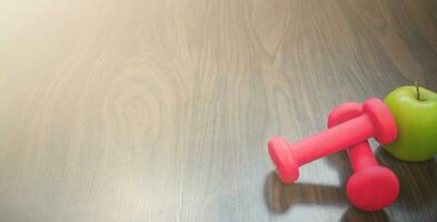 Dumbbells and apple on a wooden floor. Concepts about fitness, sport and health photo