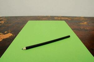 a pencil sitting on top of a green paper photo