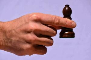 a hand holding a wooden chess piece photo