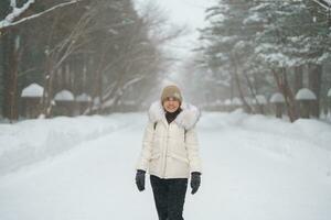 happy Traveler with Sweater and backpack walking on snow covered forest in frosty weather. Winter Travel, Adventure, Exploring and Vacation concept photo