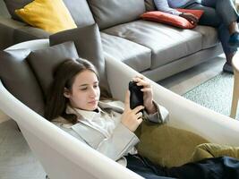 businesswoman female lady girl woman person people sleep sit sofa chair smartphone mobile tablet play look see game technology digital network cyberspace relaxation lifestyle communication cellphone photo