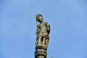 a statue of a man holding a sword on top of a building photo