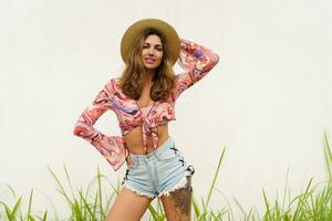 Beautiful european woman in stylish summer outfit and straw hat posing on white background. Fashion look. photo