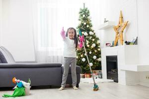 pequeño niña limpieza el Departamento antes de Navidad foto